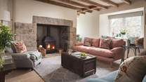 Wooden beams and an exposed stone fireplace add country-cottage ambience to the sitting room