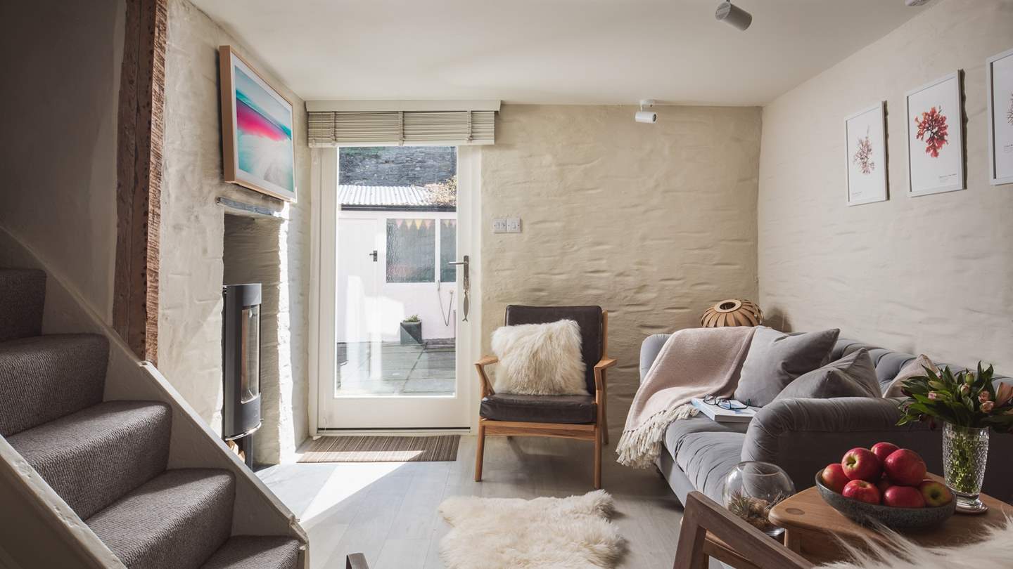 The sitting area lies to the back of the room, with a tactile grey velvet sofa and two occasional chairs 