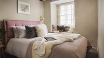 The master bedroom is super-pretty with a sumptuous king size bed with dusky pink headboard