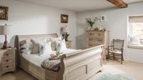 The gorgeous master bedroom has a romantic king-size sleigh bed, built in wardrobe, drawers, and garden views