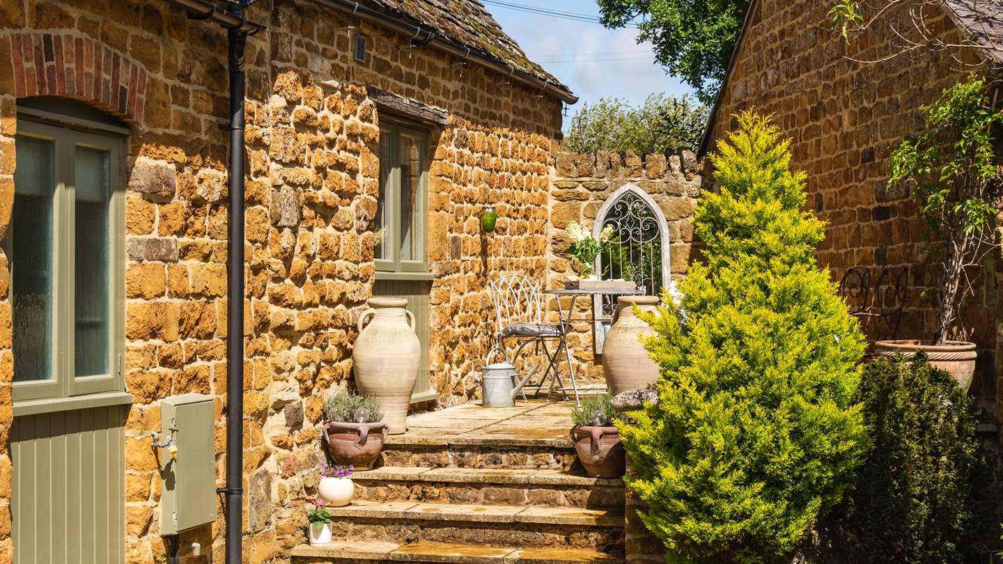 Steps lead up to the sunny terrace with bistro table and chairs