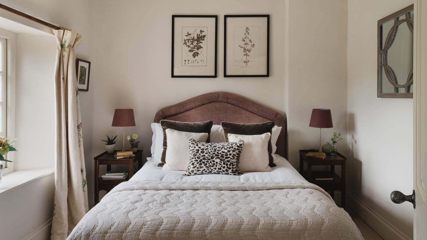The delightful master bedroom dressed in natural hues and shades of berry, has a plumptuous king size bed with views over the fairy tale garden