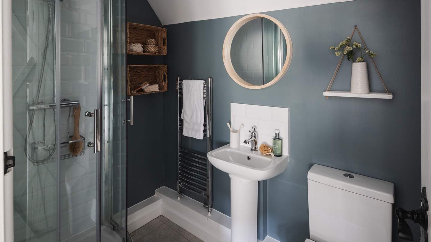 A stunning en suite shower room in soft grey and blue hues with a heated rail to keep towels warm and fluffy