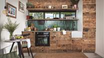 The far wall is home to the kitchen, with everything you need hidden behind upcycled wood cupboards and a polished concrete worktop