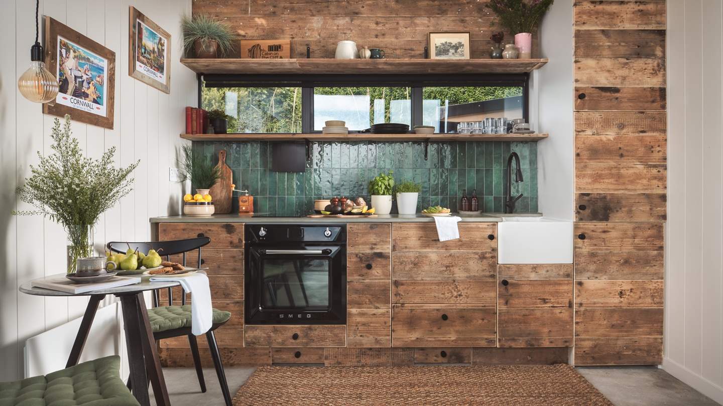 The far wall is home to the kitchen, with everything you need hidden behind upcycled wood cupboards and a polished concrete worktop