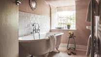 Another en suite awaits, dressed in pink and white tones with both a roll-top bath tub and separate shower