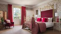 The red bedroom boasts a king-sized brass bed with built in wardrobe, original feature fireplace and antique artwork