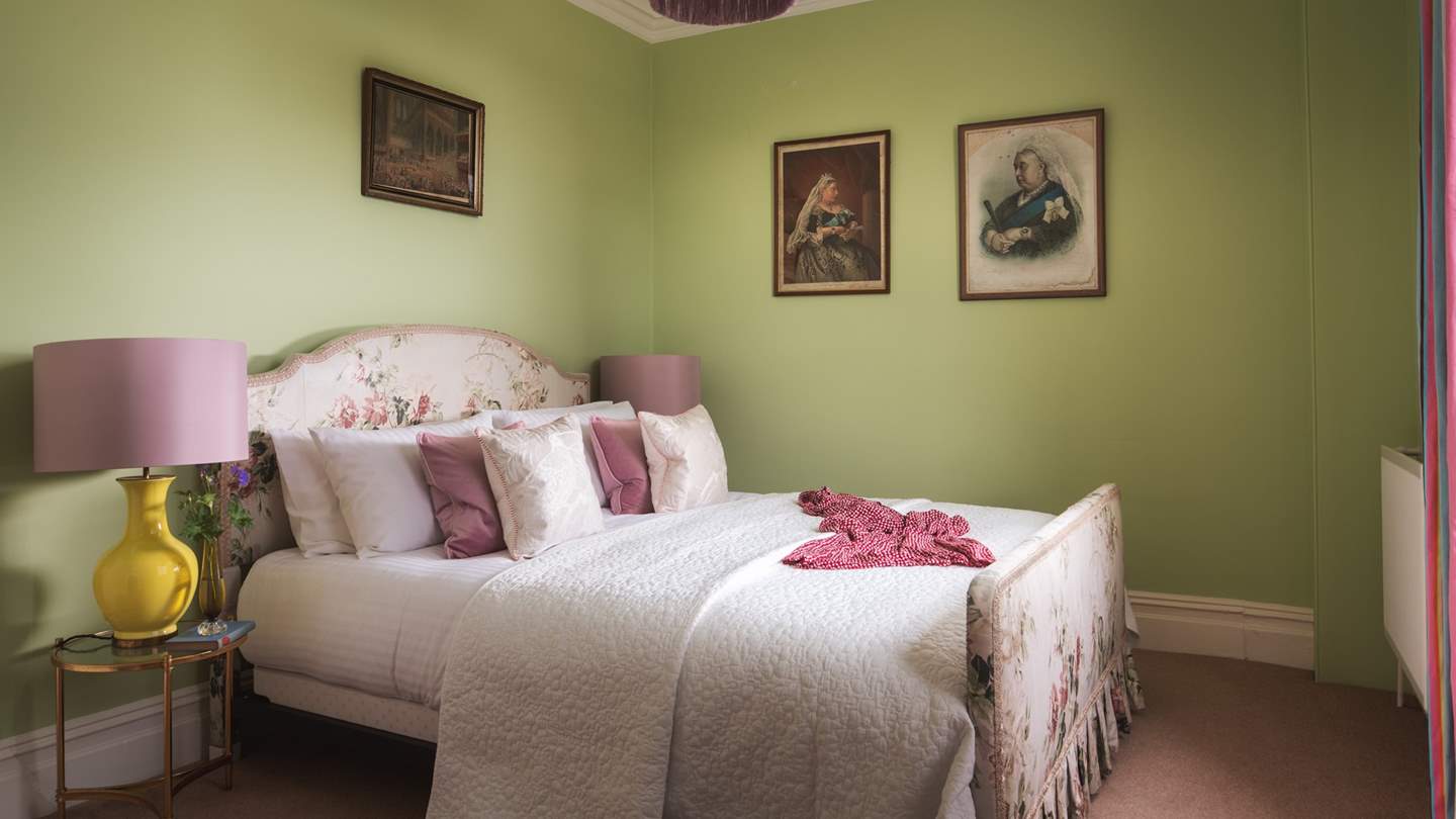 The green bedroom has an oh-so-romantic king-sized bed with floral bed head, original fireplace and built in wardrobe