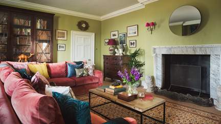 A huge L-shaped sofa is just made for sprawling out on around the vast open fire