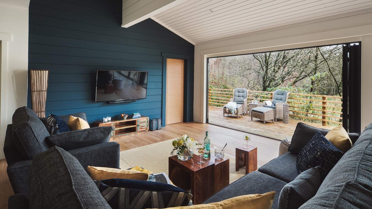 The open plan livingg area is a bright, airy space with floor-to-ceiling bi-folding glass doors that lead out on to the decking