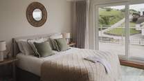 Boasting floor-to-ceiling glass windows and an oceanside deck, this dream bedroom promises a cosy king bed