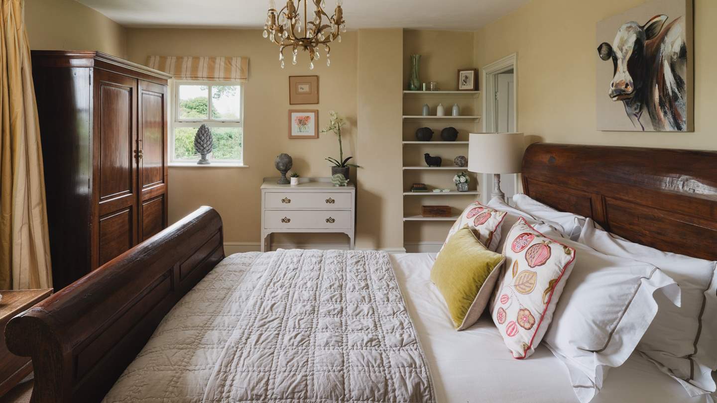 This is a pretty bedroom with an impressive, high-backed wooden king-sized sleigh bed