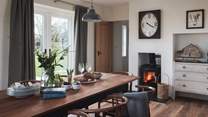 The beautiful dining table comfortably seats ten and benefits from the cosy heat of the double-sided wood burner