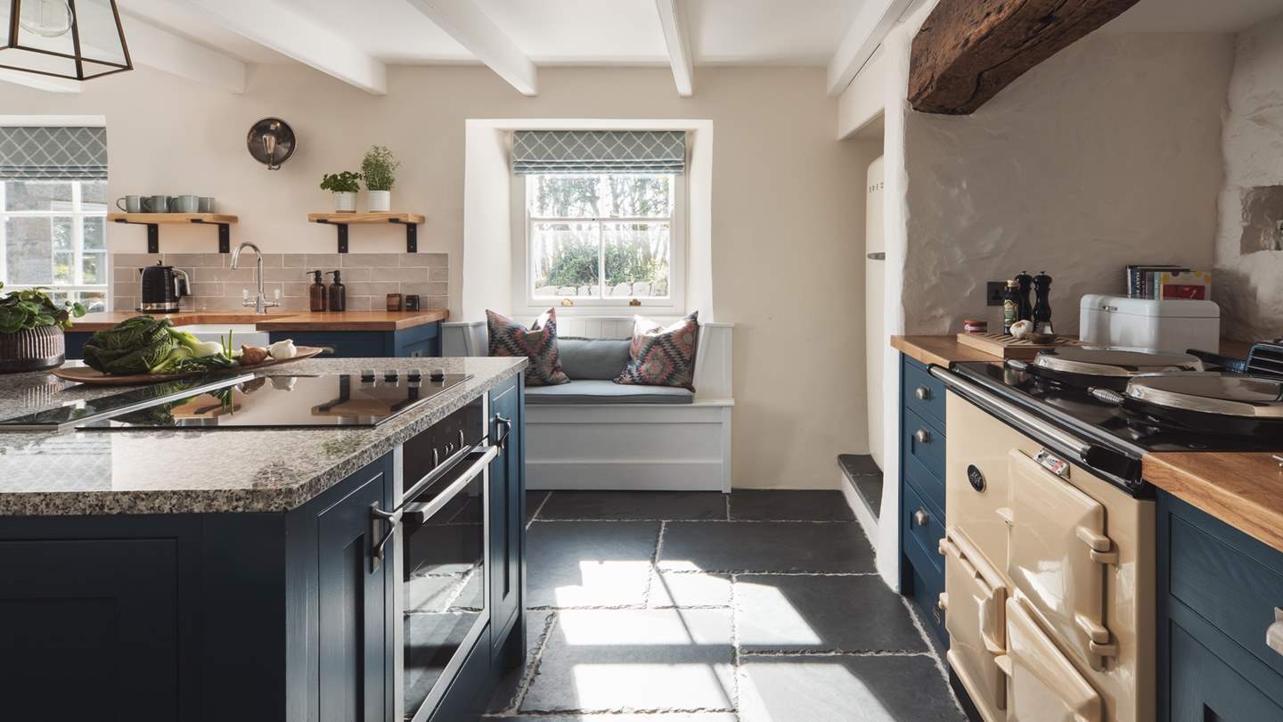 This room showcases an exquisite blend of vintage charm and modern luxury with a slate floor, whitewashed walls and views out over the sweet courtyard