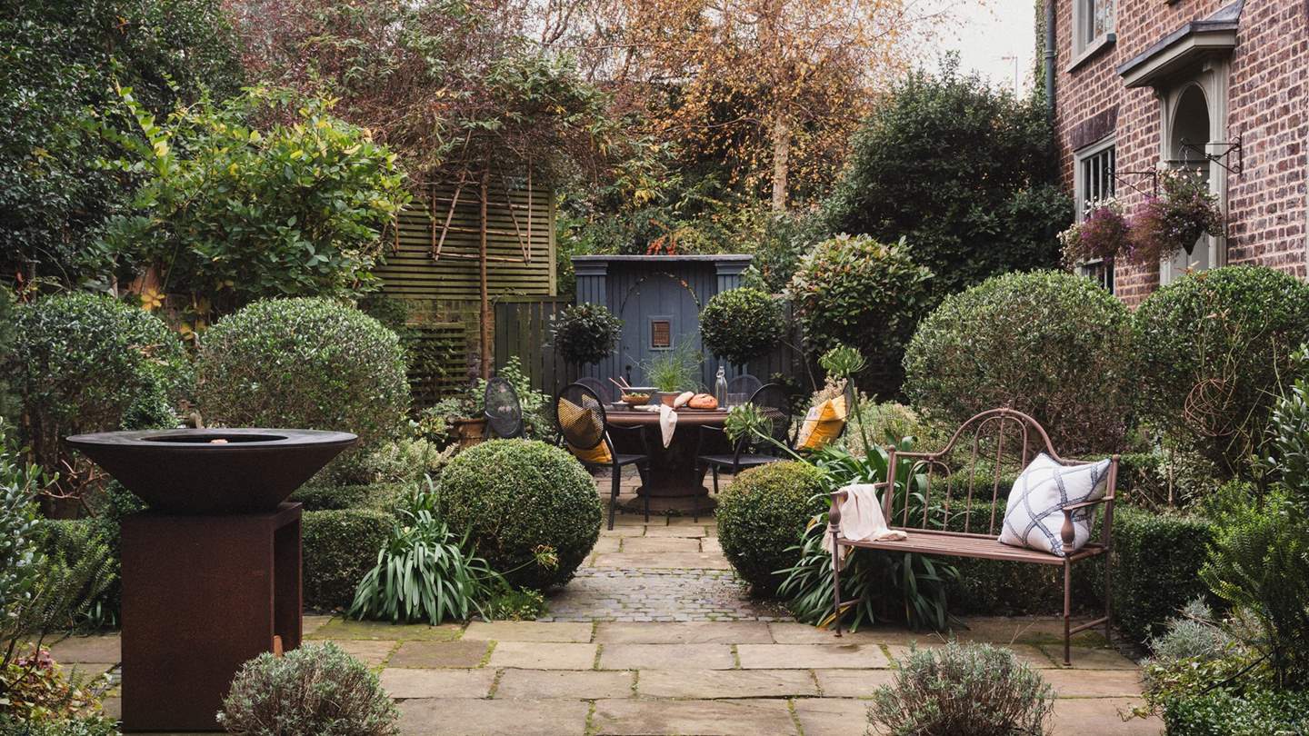 A wrought iron bench offers an additional spot to recline in front of the sculptural Ofyr firepit