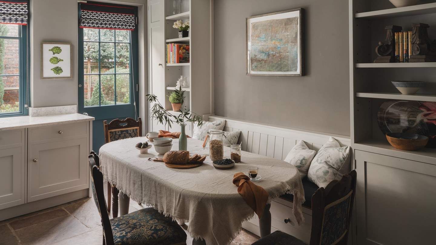 An antique dining table with chairs and a fitted bench reside for casual brunches