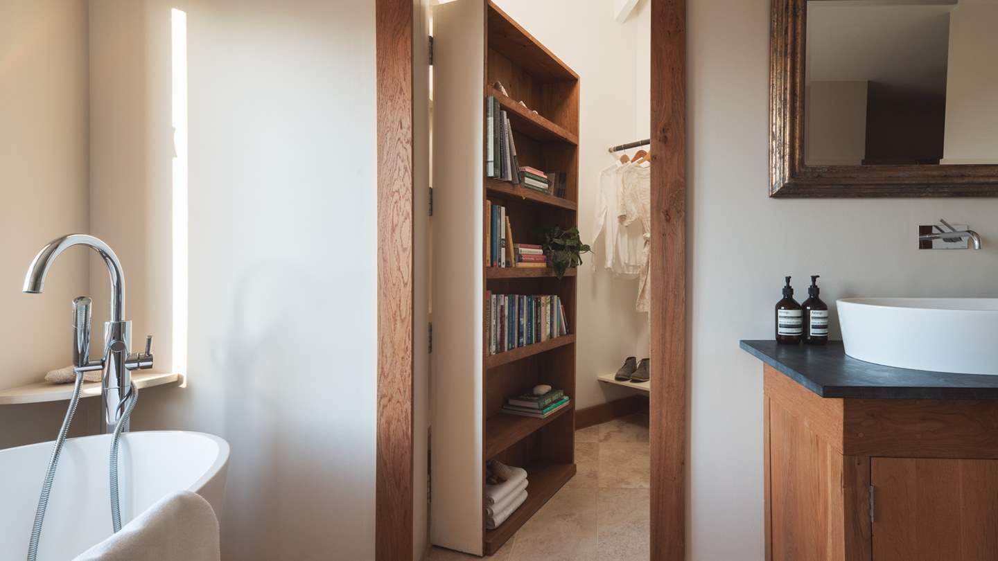 Hidden behind an oak bookcase resides the secret walk-in wardrobe