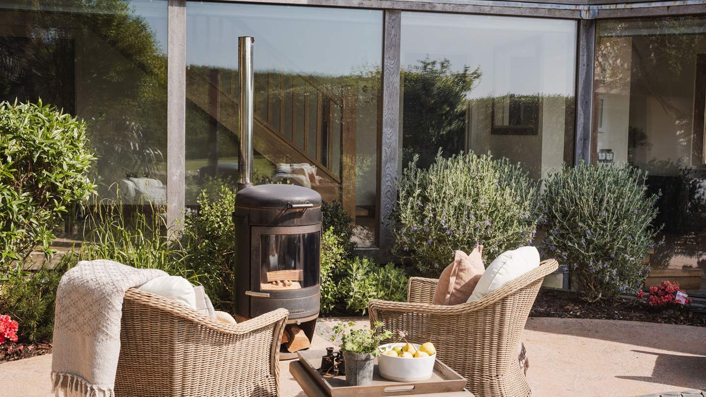 Styled with rattan furniture and comfortable seating around the wood burning stove