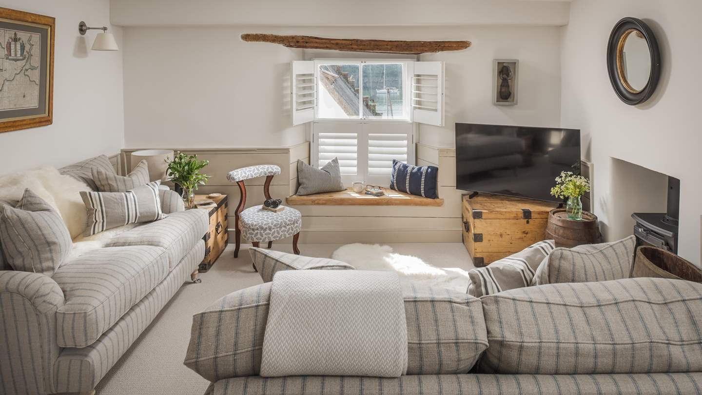 The cosy sitting room with wood burner, nautical striped sofas and stunning river views