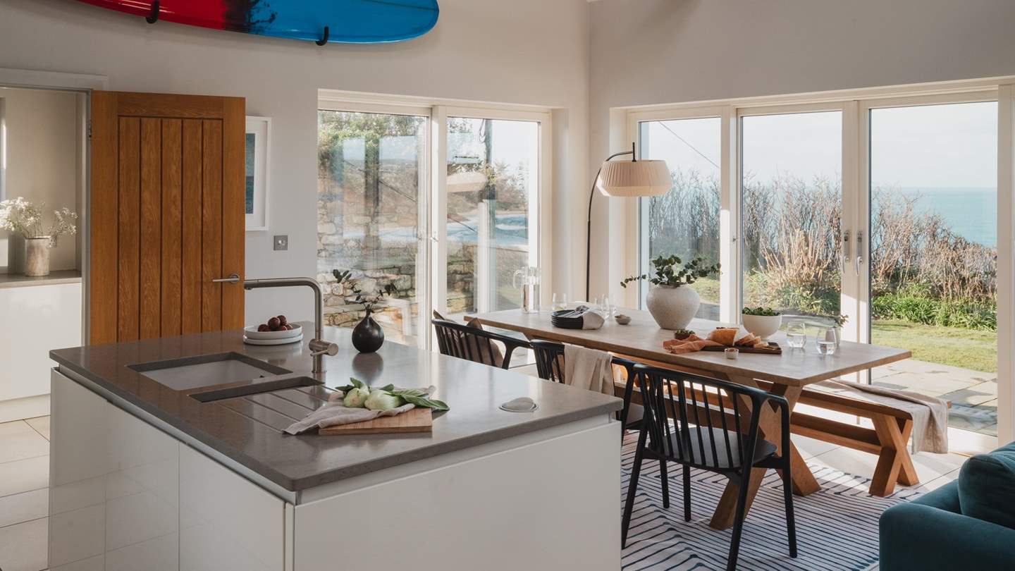 The chic kitchen with grey polished stone worktops and white drawer units, separated from the dining and living area by a large kitchen island