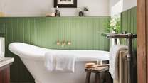 We just love the green wood panelling and the vintage wooden stool by the bath