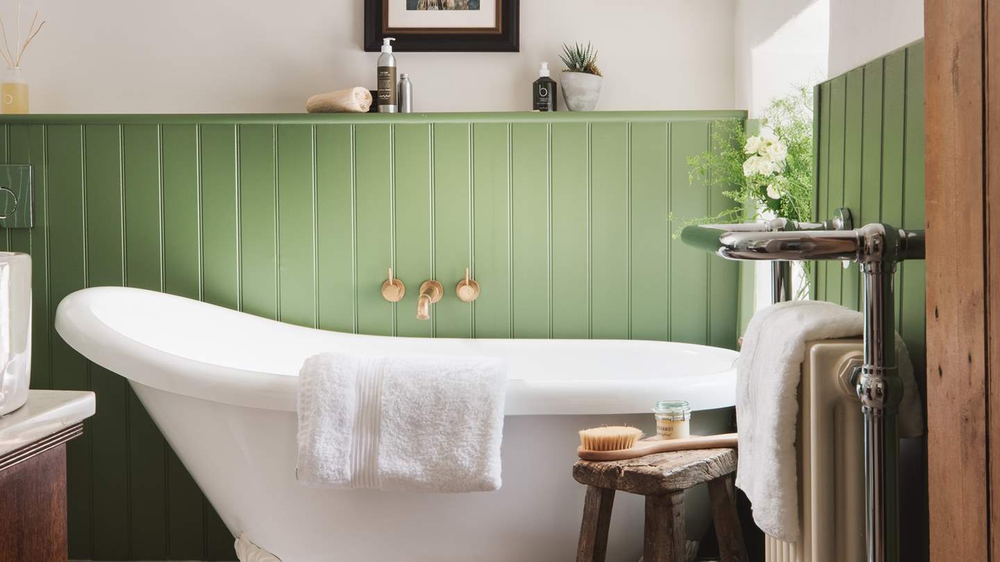 We just love the green wood panelling and the vintage wooden stool by the bath