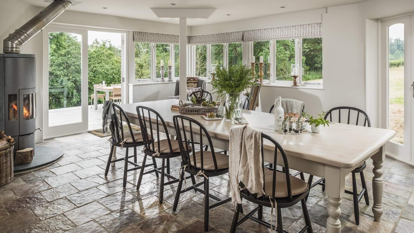 The gorgeous dining table is set beside a handsome wood burning stove, creating the cosiest set up