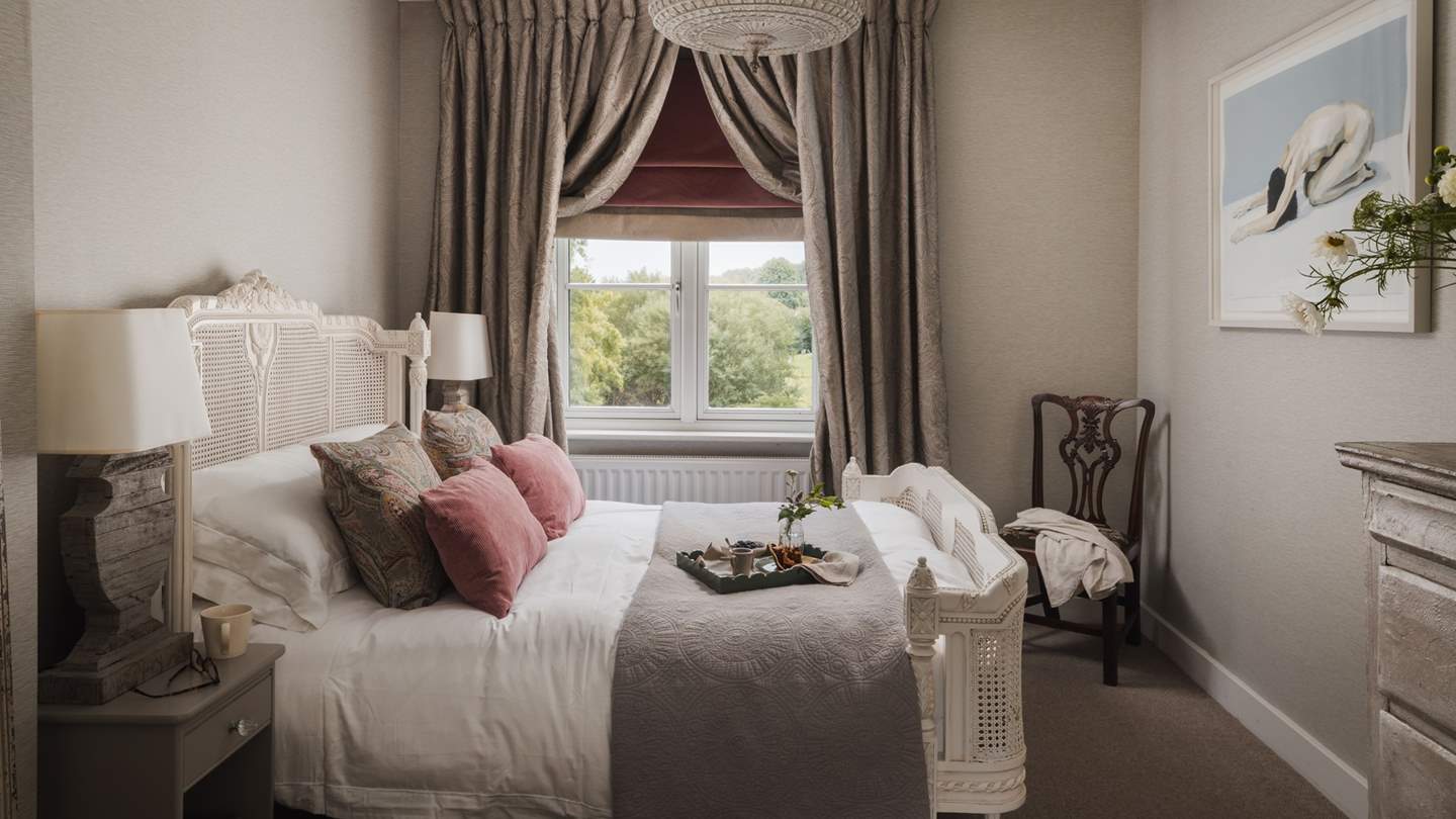 The master bedroom holds a lavish king size bed adorned in gorgeous linens, throws and cushions