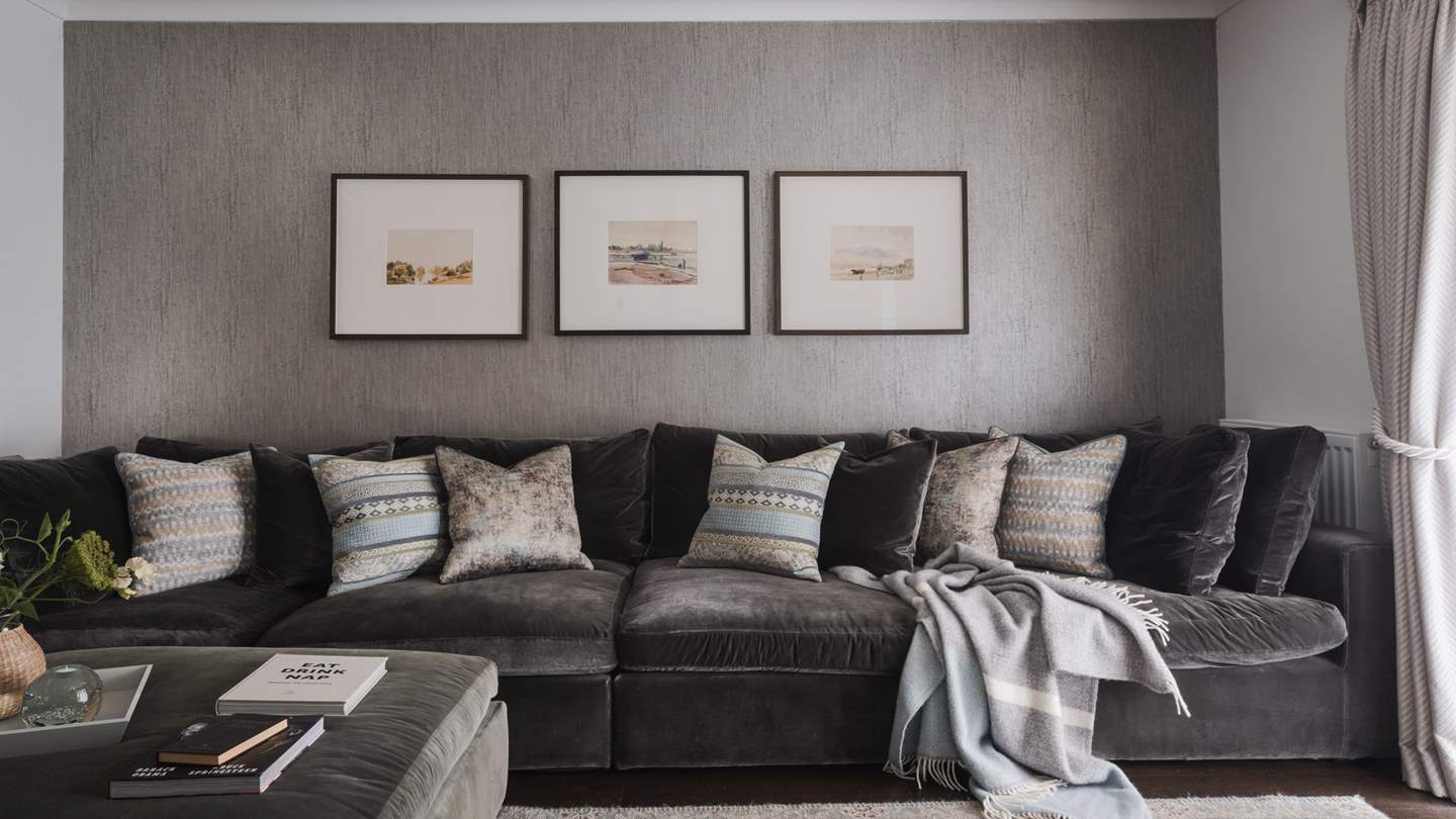 The roomy velvet sofa offering plenty of room for relaxing beside the open fireplace