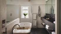 The en suite features a freestanding rolltop bath and a walk-in shower, offering a sanctuary for peaceful pampering