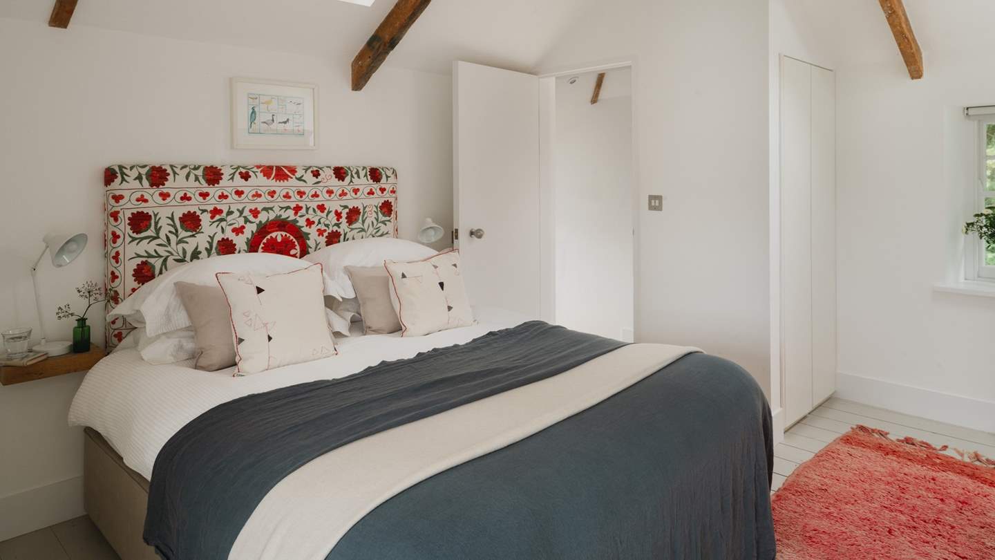 The sweet second bedroom home to a bespoke botanical headboard and cloud-soft linens