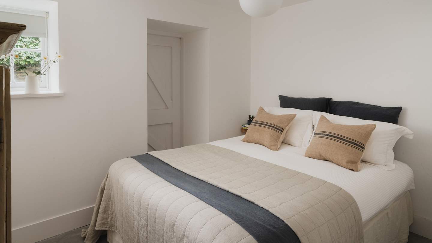 The delightful fourth bedroom dressed in calming hues has a comfy double bed and plump pillows 