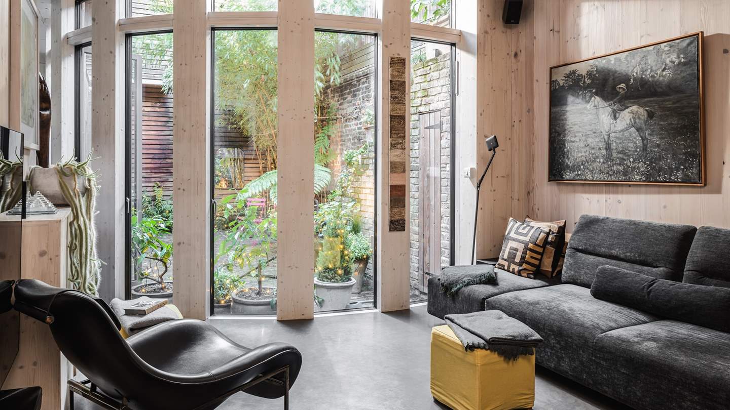 The chic yet comfy sitting area is just a dream to relax in, boasting floor-to-ceiling windows which flood the polished concrete floor with dappled light