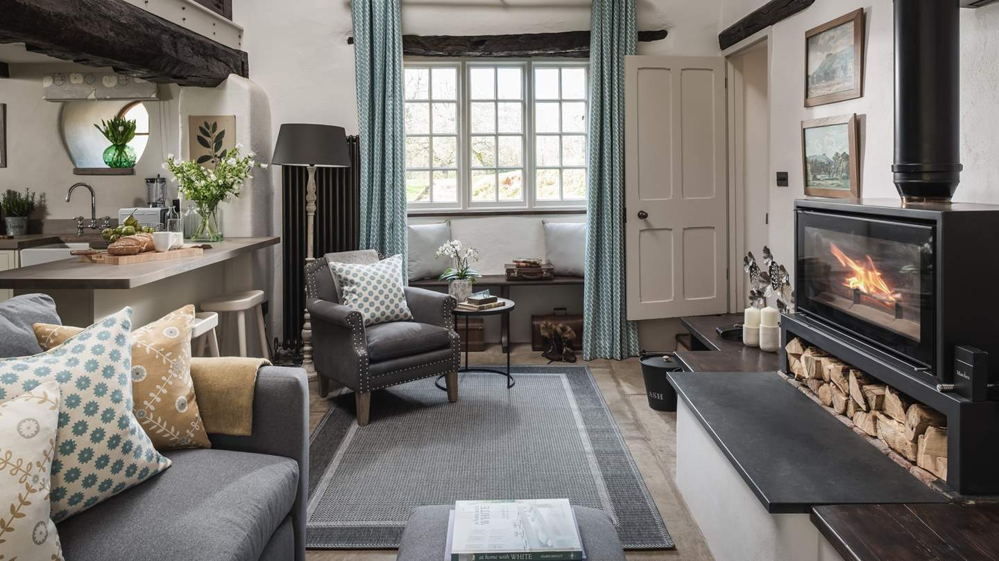 A wood burning stove radiates warmth in winter and an alcove window with a period lintel affords captivating garden views