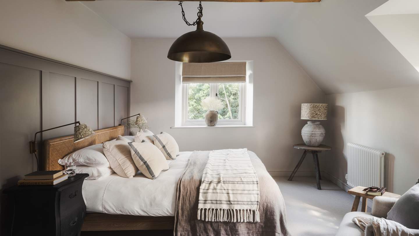 The second bedroom holds a super king-sized bed dressed in neutral tones, with an air of curated calm throughout this soothing space