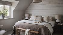 The calming hues of bedroom five, with a super king-sized bed and rustic, Neptune wood-clad feature wall
