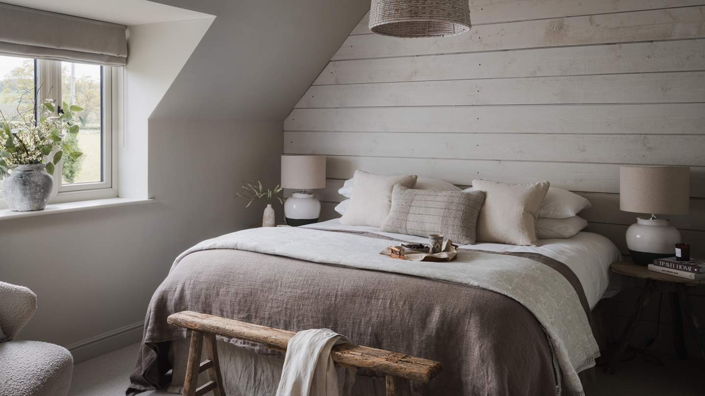 The calming hues of bedroom five, with a super king-sized bed and rustic, Neptune wood-clad feature wall