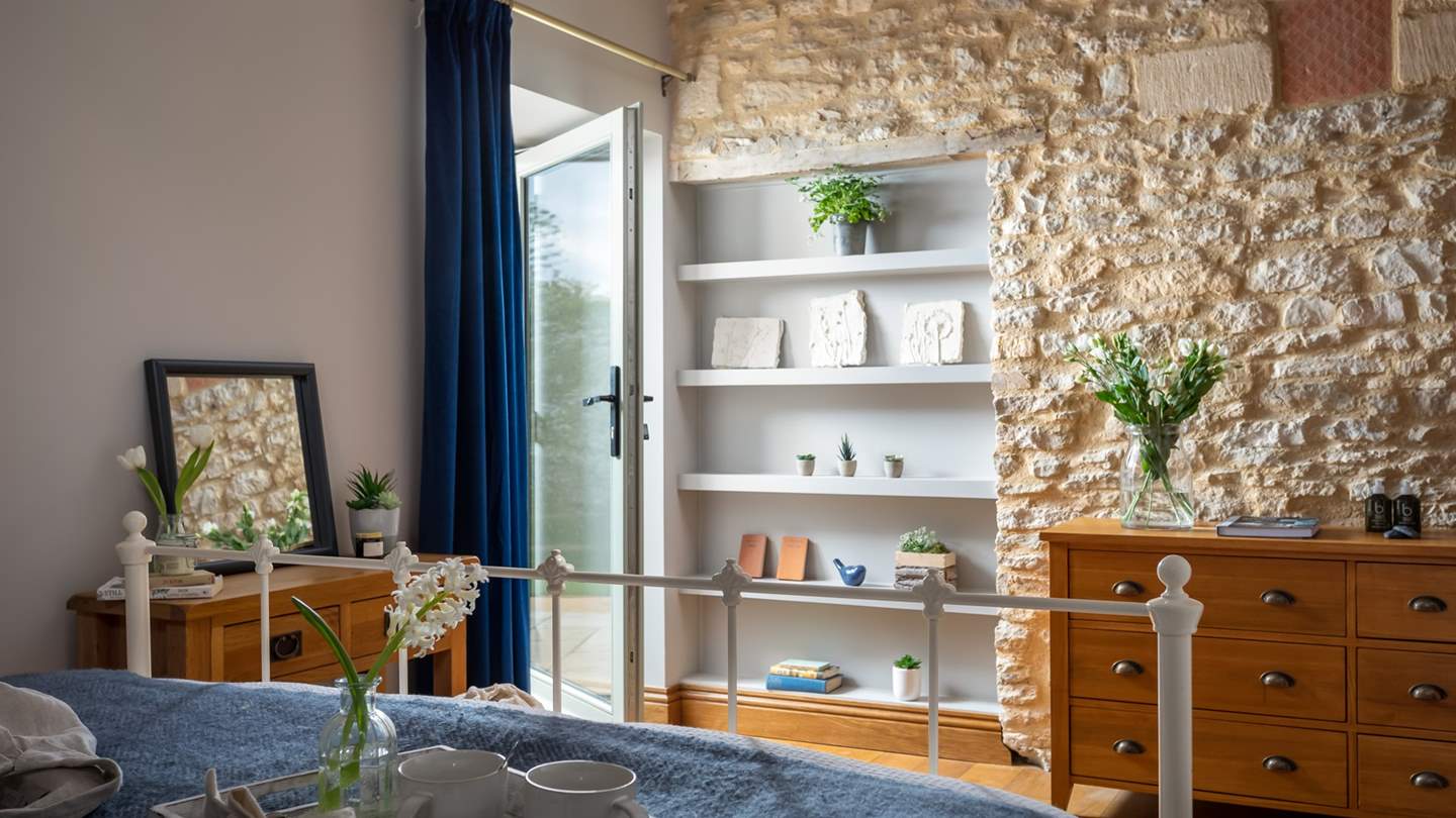 With feature Cotswold stone wall and door leading outside, this is a gorgeously romantic bedroom