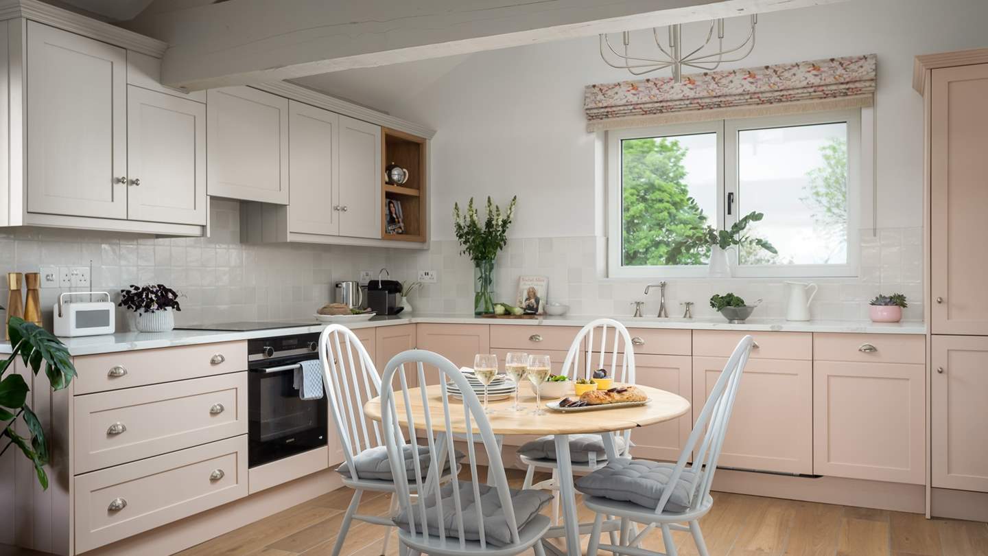 The kitchen with blush pink cabinetry comes fully equipped with everything you may require during your staycation