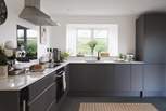 At the other end of the room lies the kitchen, complete with chic dark cabinets and white worktops