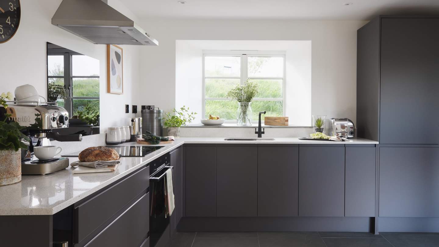 At the other end of the room lies the kitchen, complete with chic dark cabinets and white worktops