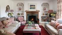 The spacious sitting room is styled in warm colours of oat and tempered reds