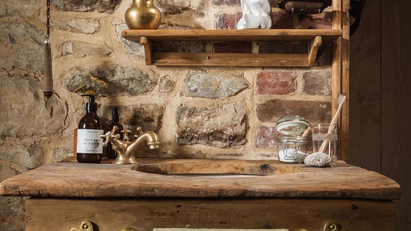 The bathroom is decorated both in tiles and exposed brick and stone with rustic fixtures and fittings