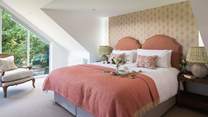 The master bedroom, with vaulted ceiling and huge glass window is a tranquil space