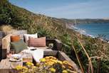 The fabulous oak bench seat is a great place to settle down and admire the wild Cornish coastline