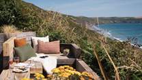 The fabulous oak bench seat is a great place to settle down and admire the wild Cornish coastline