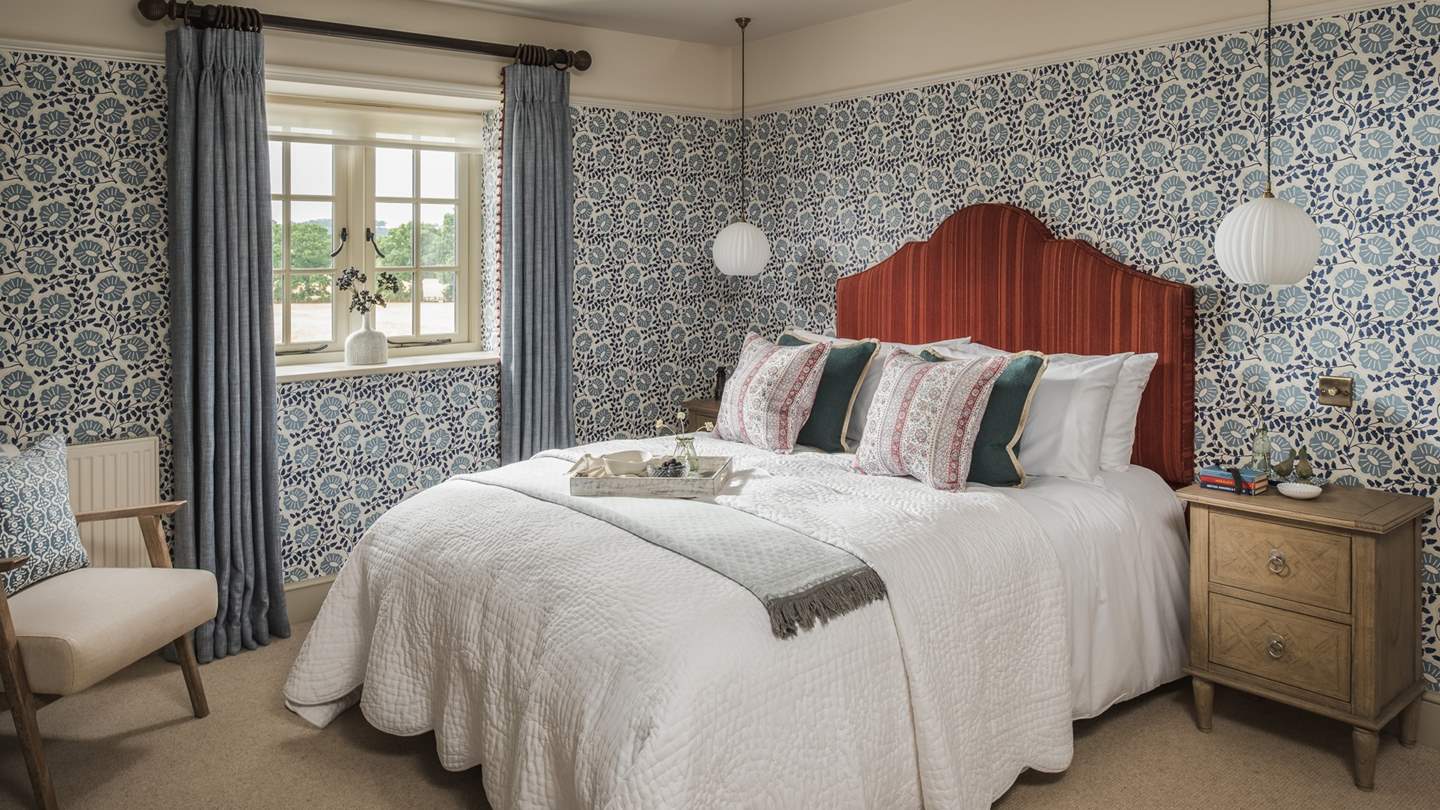 Bold and beautiful, the master bedroom is furnished with patterned blue wallpaper