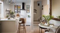 The kitchen area is light and bright, with crisp white cupboards and worktops 