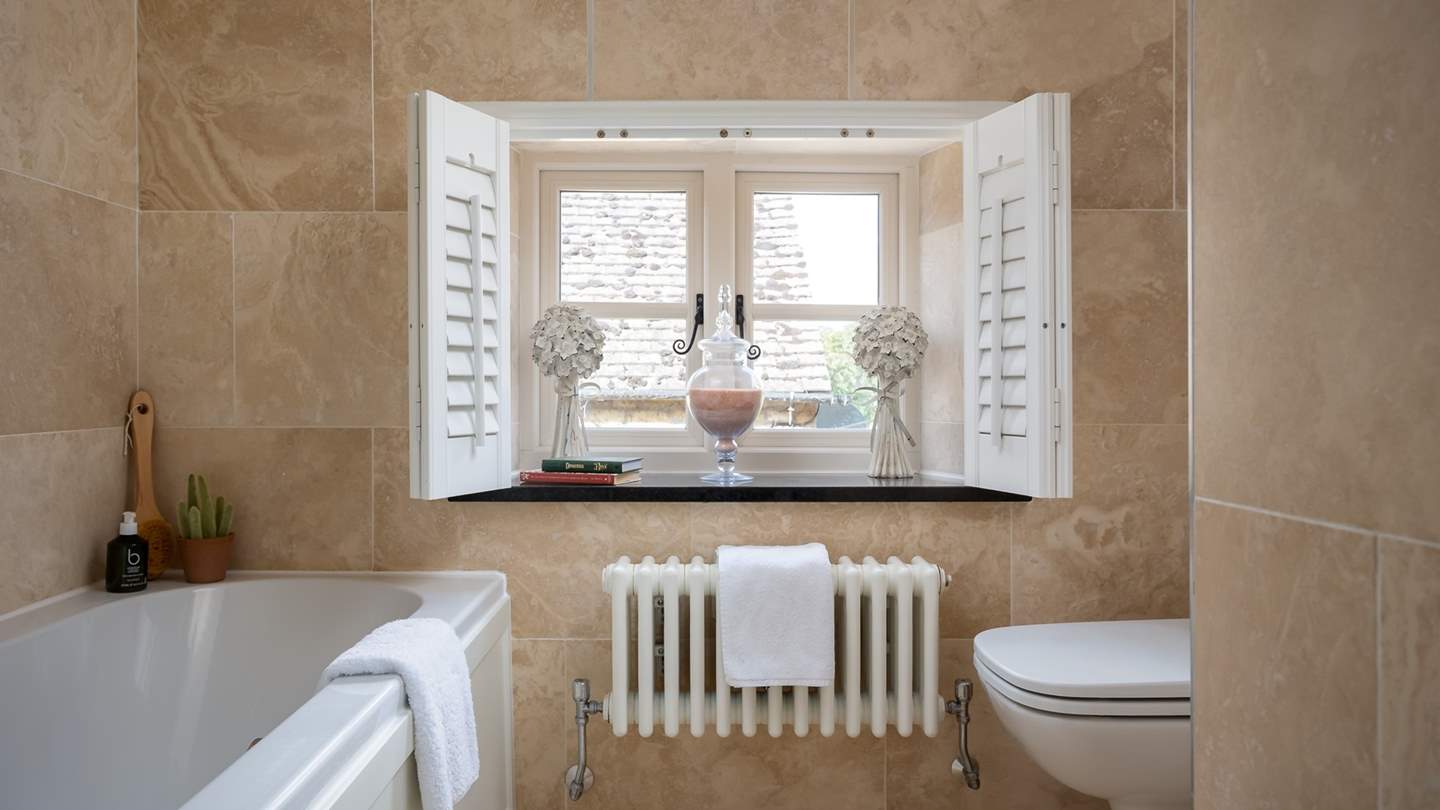 We just adore the elegant French shutter windows in the marble tiled family bathroom 