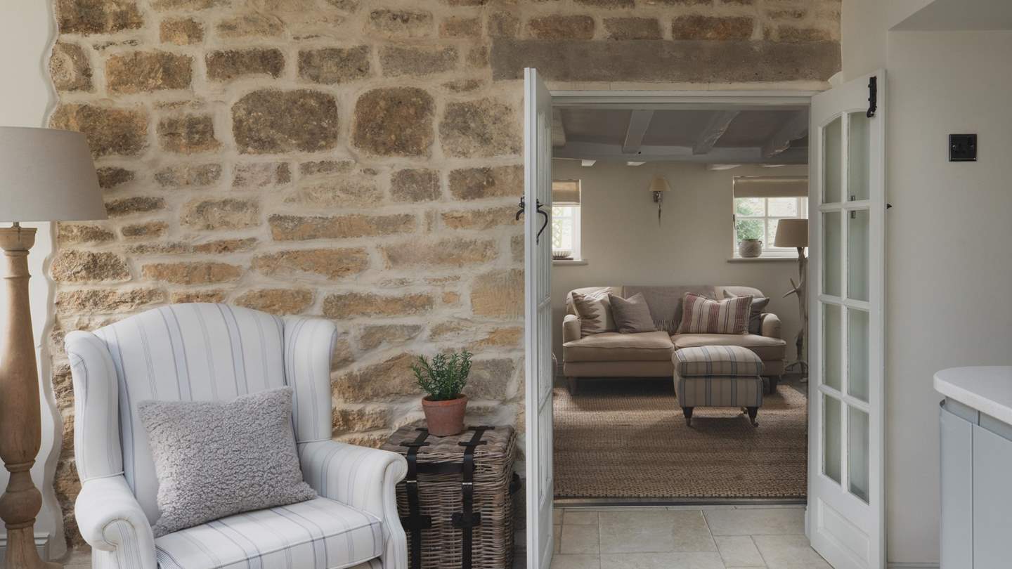 With an exposed Cotswold stone feature wall, where two opulent armchairs rest - a blissful nook for settling down with a book